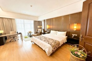A hotel room with a bed, desk, chair, and a small table. - Huasheng Shaxian Boutique Hotel (Sanming)