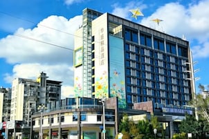 Un edificio de varios pisos con un letrero vertical llamativo, una estrella en la parte superior y un cielo despejado.