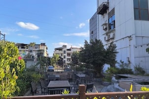 Un patio con mesas al aire libre, rodeado de edificios, bajo un cielo despejado.