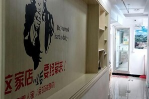 A hallway with a wall featuring a mural of two figures and text in a foreign language. - Fenggang Luosan Inn (Fenggang)