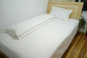 Una cama con una colcha blanca y una toalla blanca doblada.