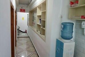 Un couloir étroit, avec un distributeur d’eau et un extincteur fixés au mur.