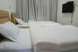 Una habitación de hotel con dos camas, un televisor en la pared y una cortina.
