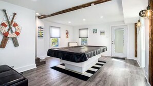 A modern bedroom with a large bed, wooden beams, and a view of the outdoors. - Castaway Villas: Perfect Group Getaway – Heated Pool & Hot Tub Access (New Buffalo)