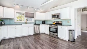 A modern kitchen with white cabinetry, a stainless steel oven, and a microwave. - Castaway Villas: Perfect Group Getaway – Heated Pool & Hot Tub Access (New Buffalo)