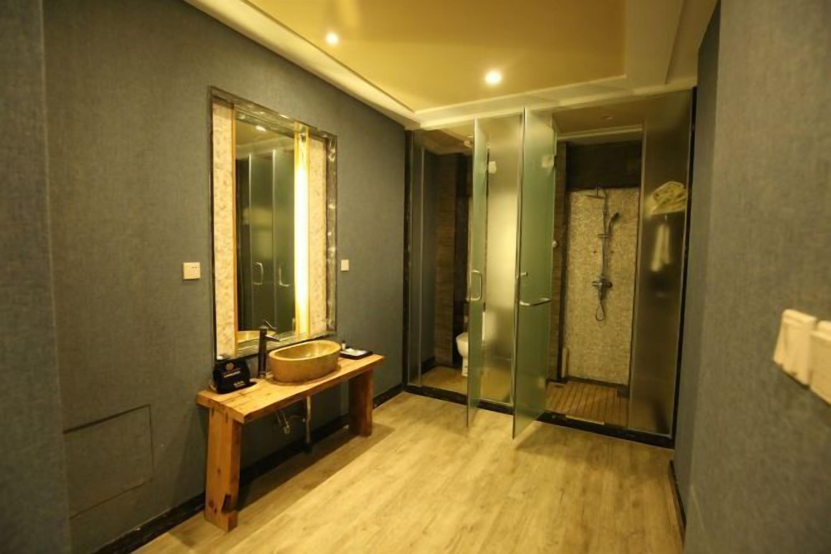 A modern bathroom with a wooden vanity, a large mirror, and a glass shower enclosure.