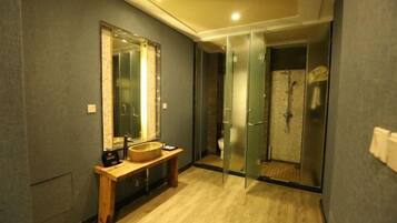 A modern bathroom with a wooden vanity, a large mirror, and a glass shower enclosure.