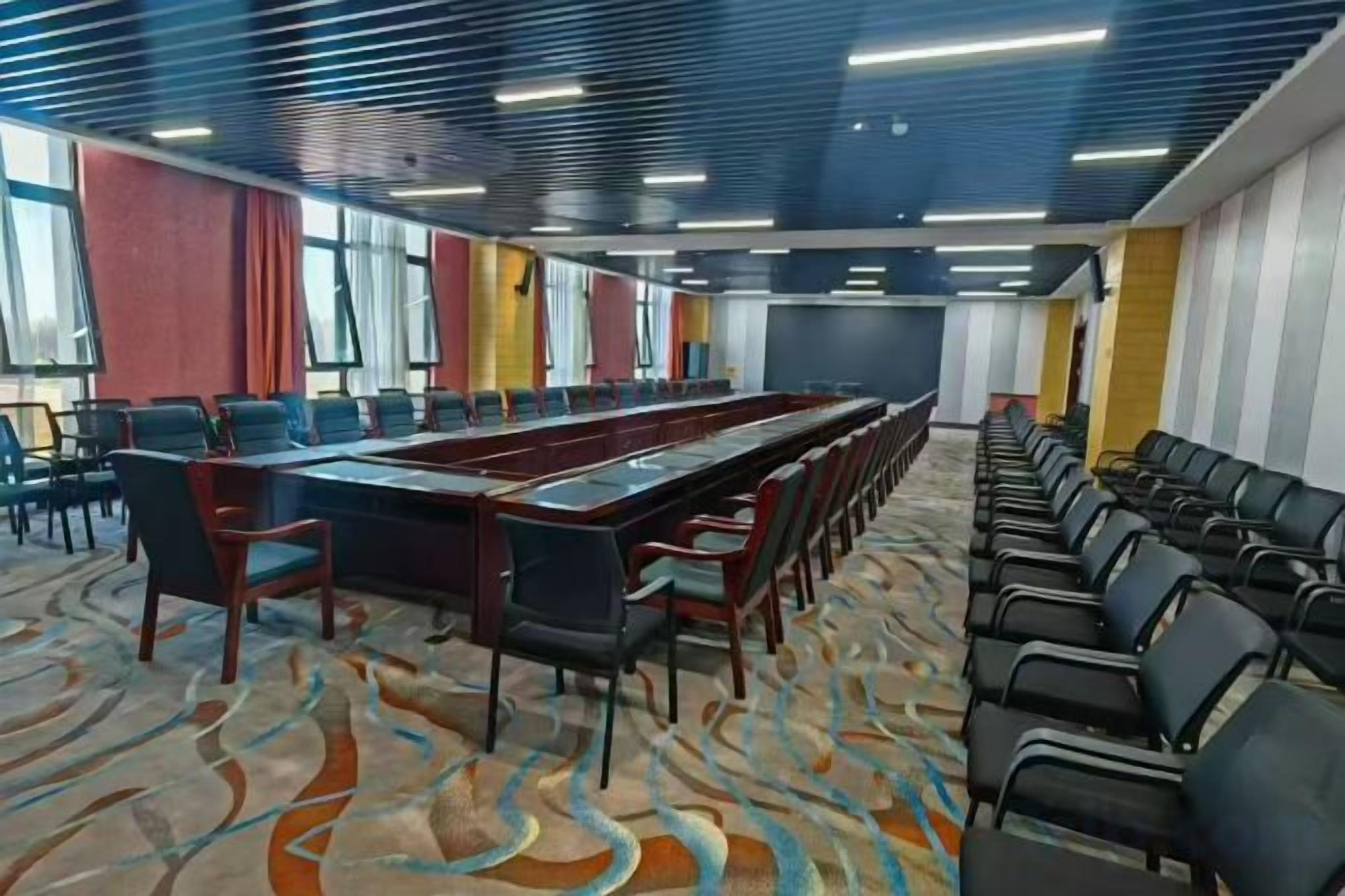 Una sala de conferències amb una taula llarga, cadires i una catifes amb dibuixos.