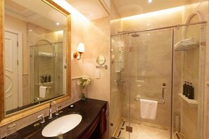 A modern bathroom with a large mirror, a sink, a glass-enclosed shower, and a towel rack.