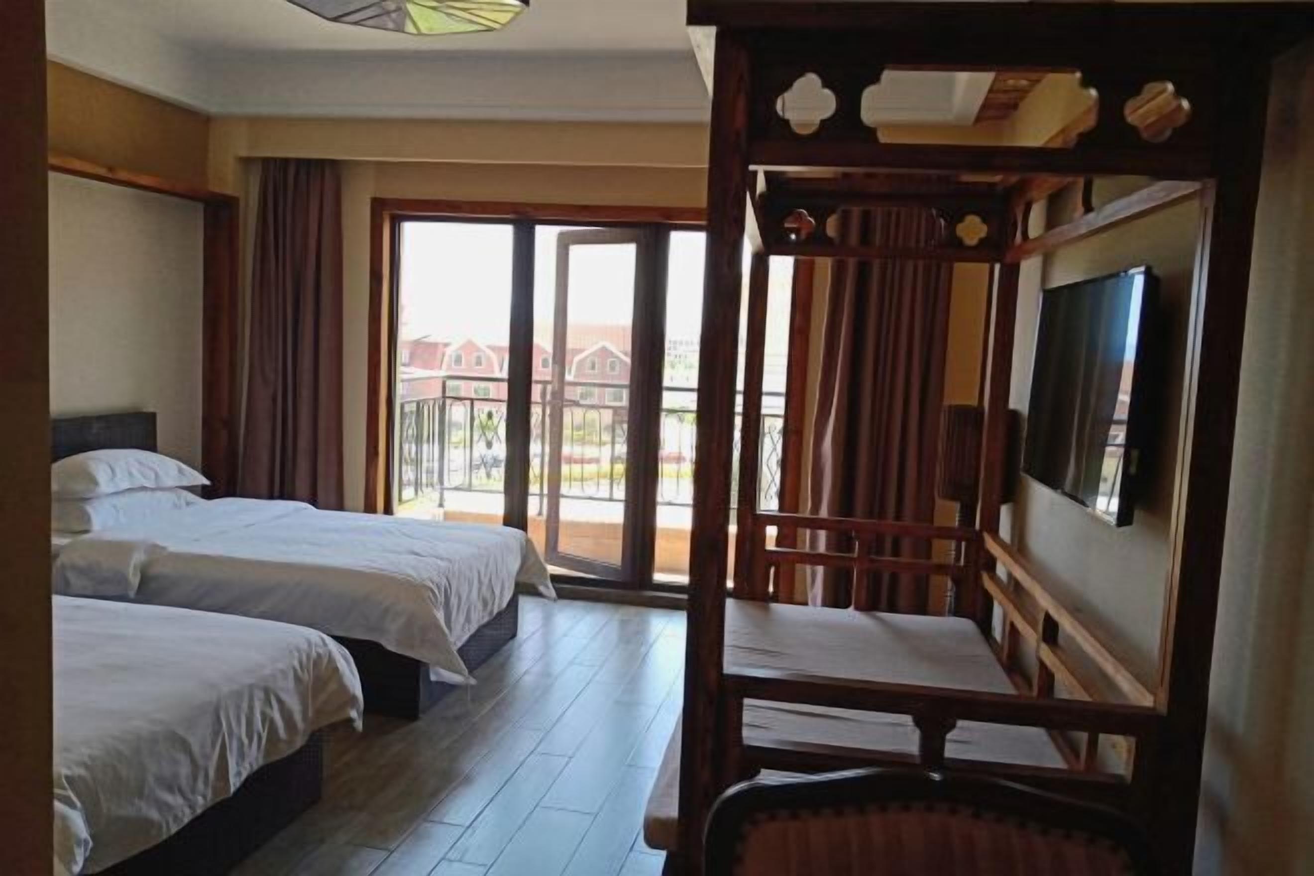 A hotel room with two beds, a balcony, and a TV.