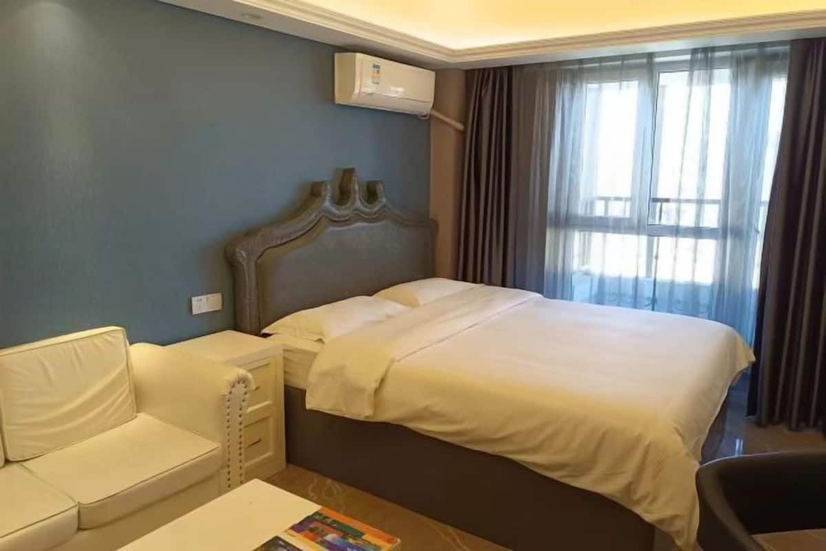 Ein Hotelzimmer mit einem Bett, einer weißen Couch, einem kleinen Tisch und einer Klimaanlage.