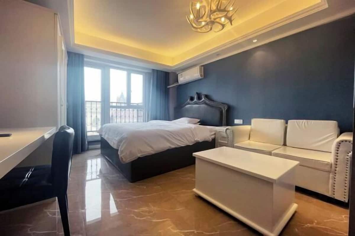 Ein modernes Hotelzimmer mit einem Bett, einer weißen Couch, einem Schreibtisch und einem Chandelier.