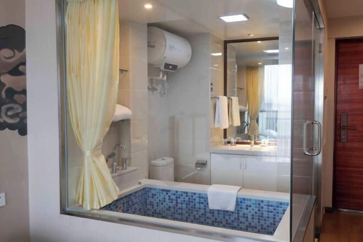 Ein modernes Badezimmer mit einer gläsernen Eckbadewanne, einer Glasdusche und einer sichtbaren Toilette.