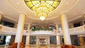 A spacious lobby with a large chandelier, columns, and a circular seating area. - Baodi Spring Town (Fuxin County)