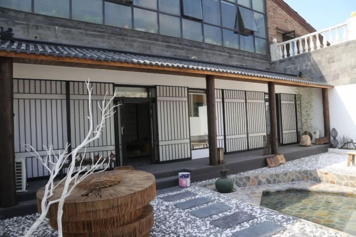 Un bâtiment traditionnel avec un toit en tuiles, une cour en pierre et un banc en bois.