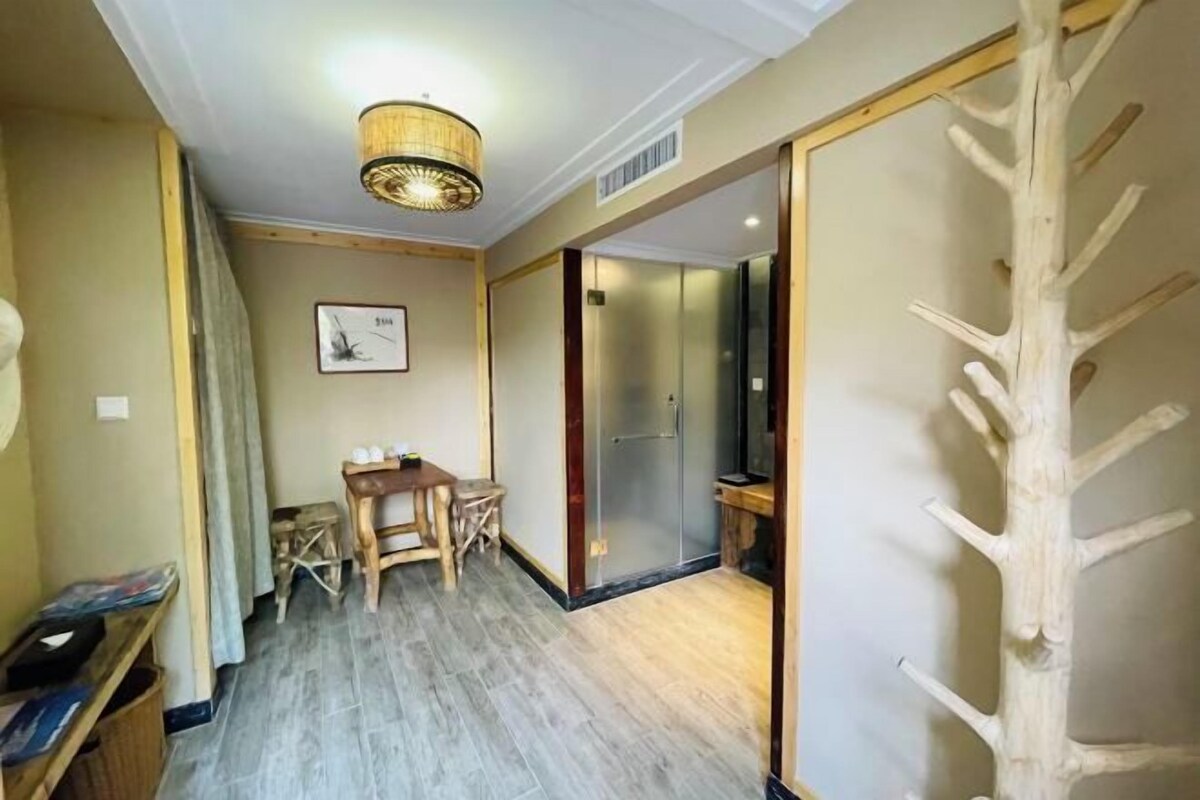 A room with a wooden floor, a dining table with chairs, a hanging light fixture, and a sliding door with a tree-like design.