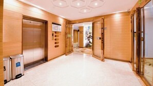 A modern elevator with a wooden finish, a clean floor, and a ceiling with hexagonal light fixtures. - Kailin International Hotel (Shenzhen Guangming Street subway station) (Shenzhen)