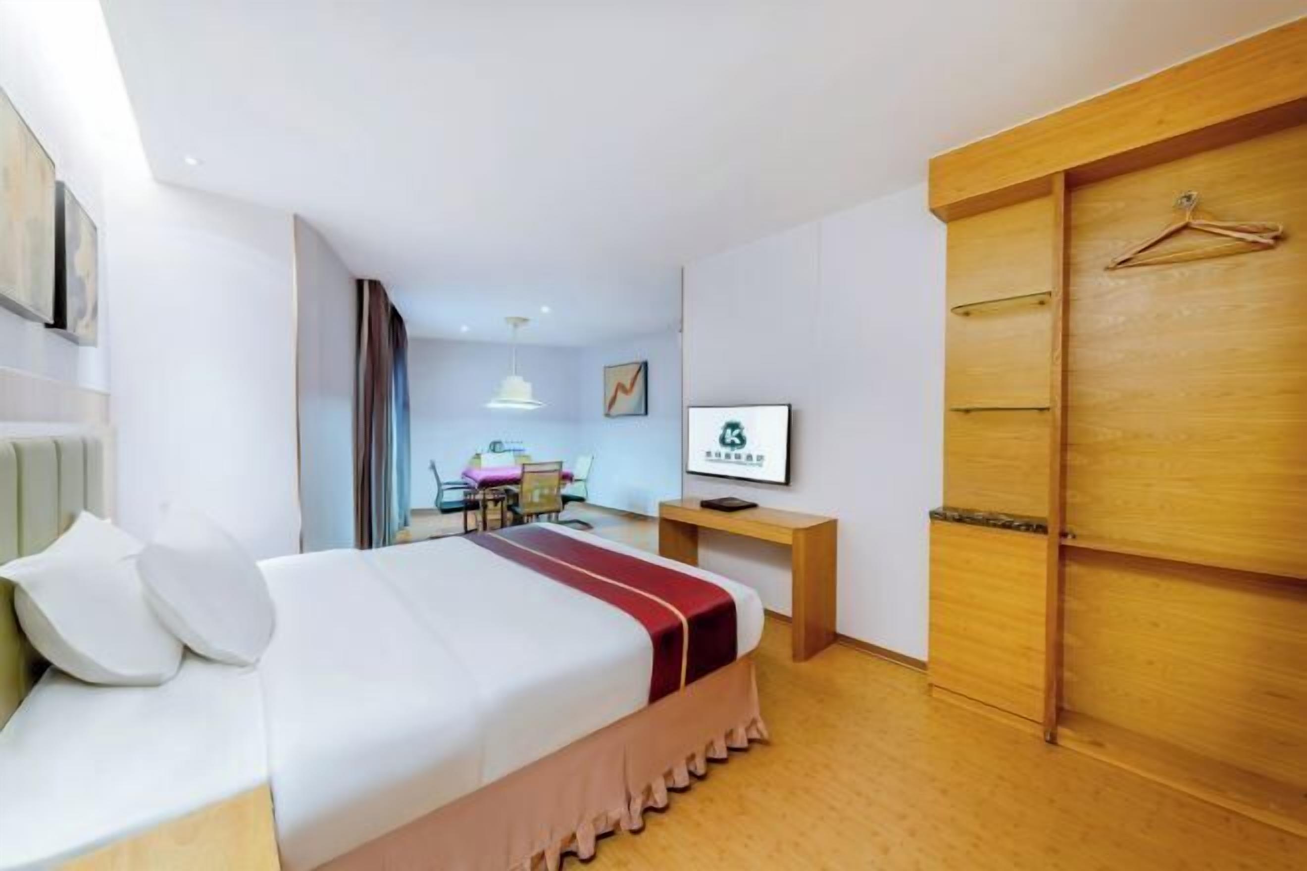 A hotel room with a bed, a desk, a chair, a wardrobe, and a television.