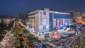 A modern building with illuminated signage and a busy street in the foreground. - Kailin International Hotel (Shenzhen Guangming Street subway station) (Shenzhen)