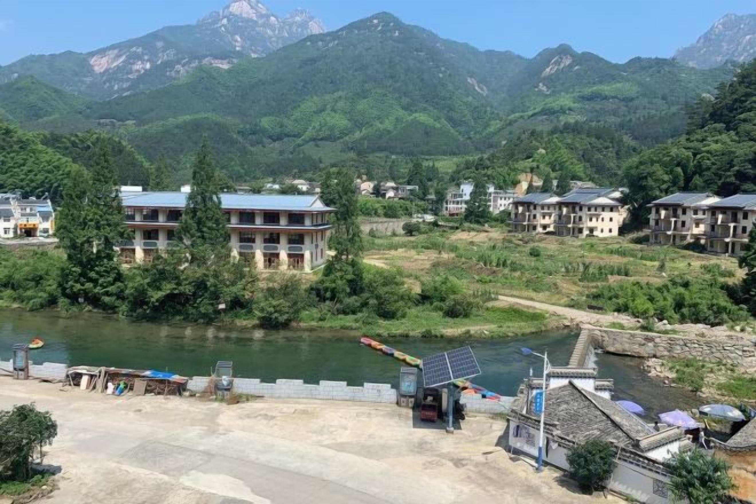 A riverside view with buildings, a bridge, and mountains in the background.