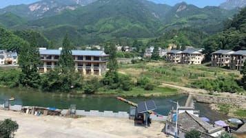 A riverside view with buildings, a bridge, and mountains in the background.