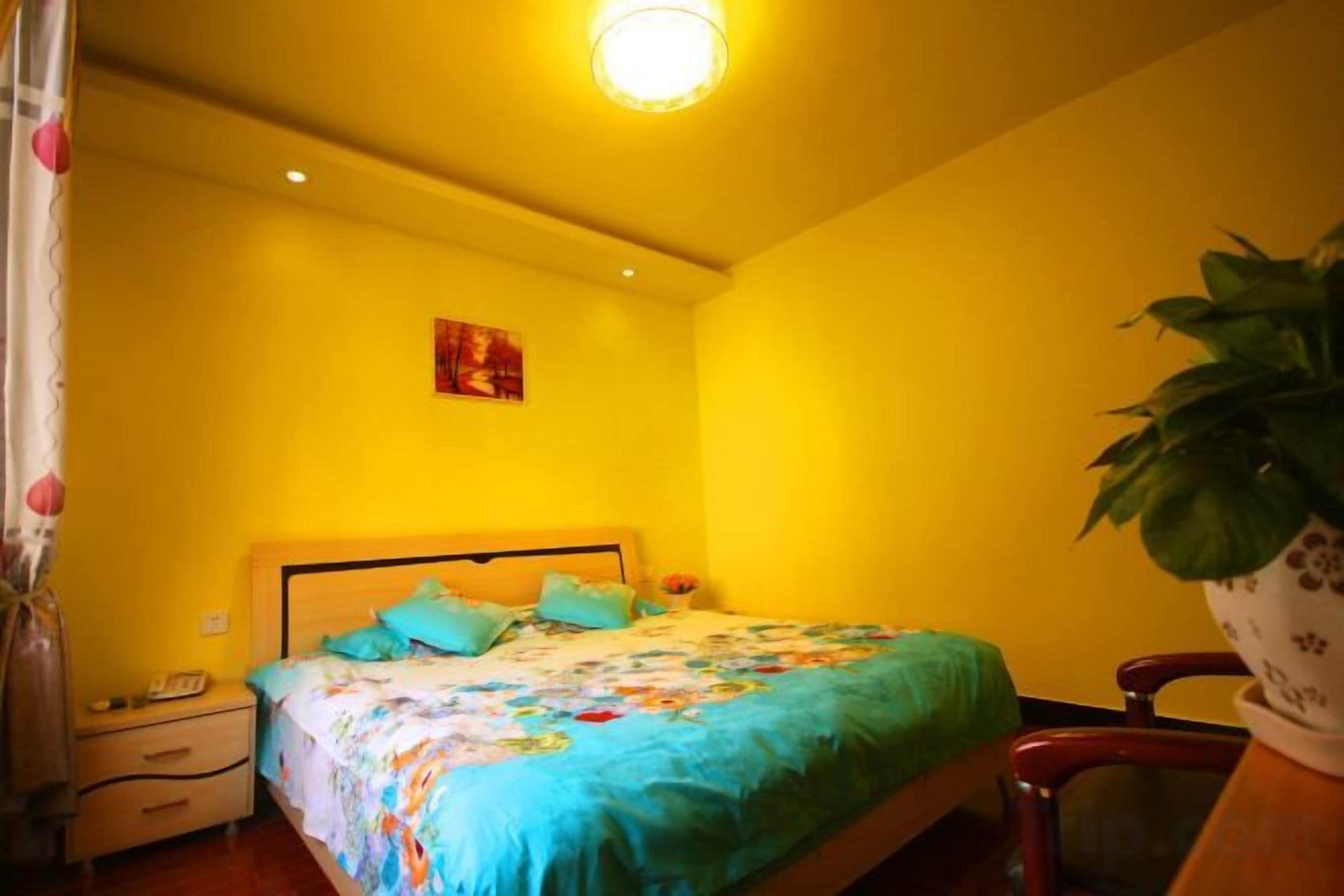 Une pièce comprenant un lit, une table de chevet, une chaise et une plante en pot.