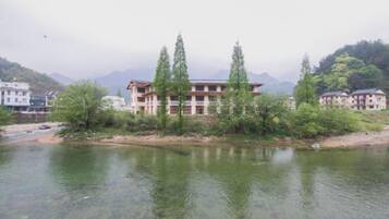 A building with a traditional architectural style, situated beside a calm river with clear water.