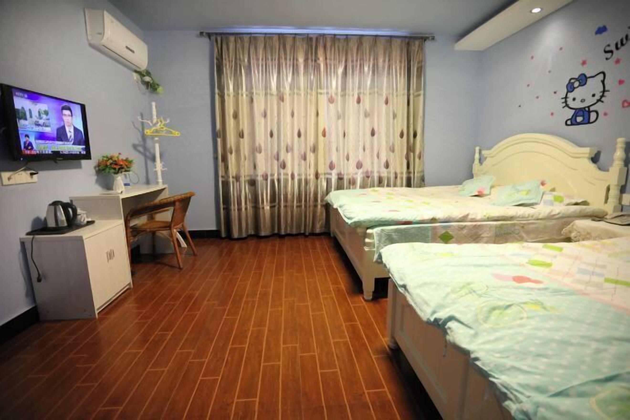 Ein Hotelzimmer mit zwei Betten, einem Schreibtisch mit Stuhl, einem Fernseher und einem Vorhang.