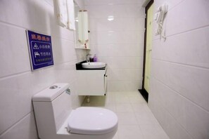 A small, clean bathroom with a toilet, sink, and mirror. - Haiyun Inn (Huangshan City)