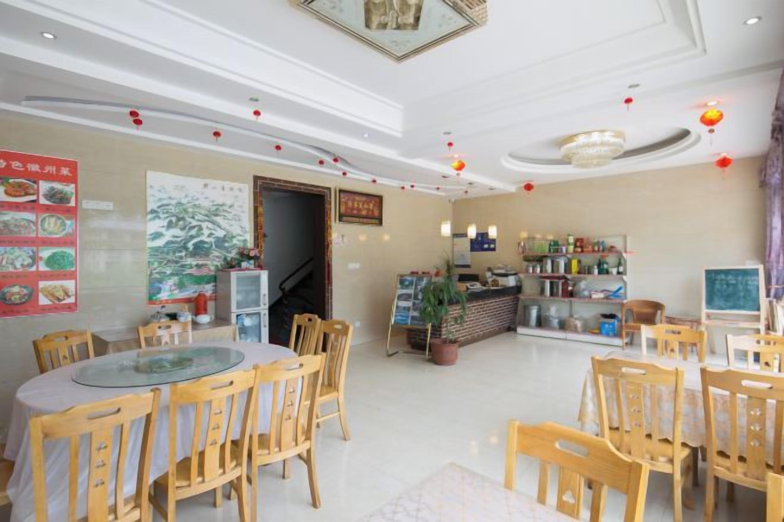 A restaurant with round tables and chairs, a counter with a menu, and a wall with food images.