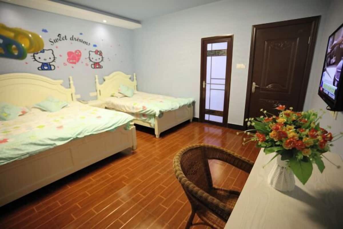 A bedroom with two beds, a wicker chair, a TV, and a wall decoration.