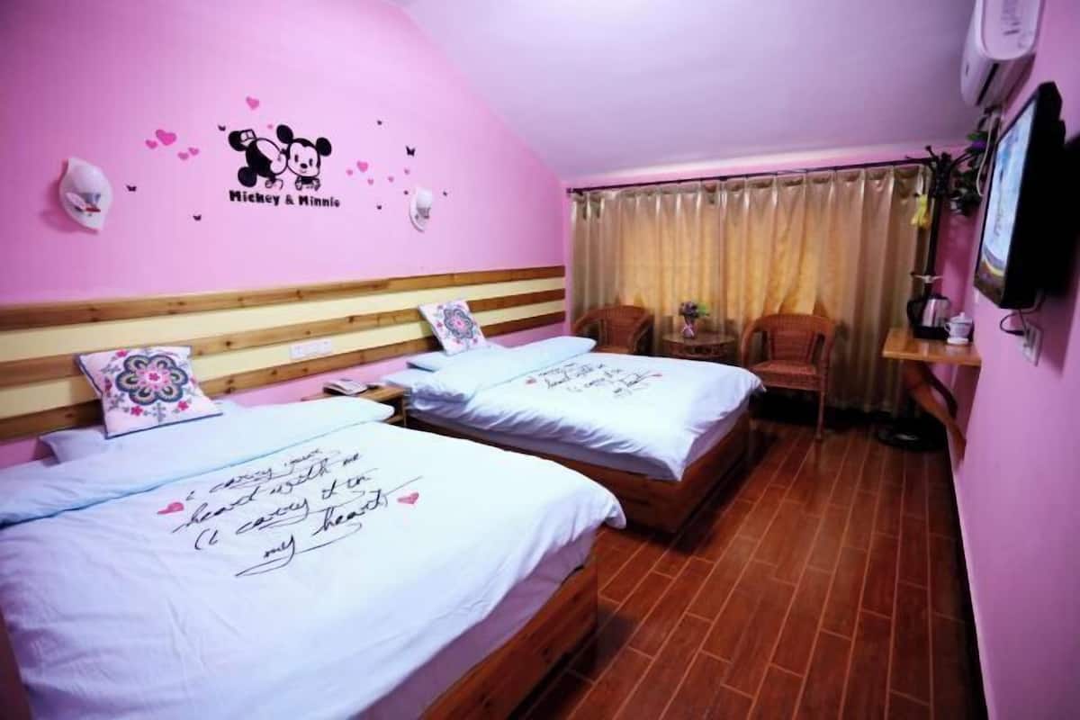 A room with two beds, a wooden headboard, a pink wall with Mickey & Minnie decorations, a TV, and a curtain.