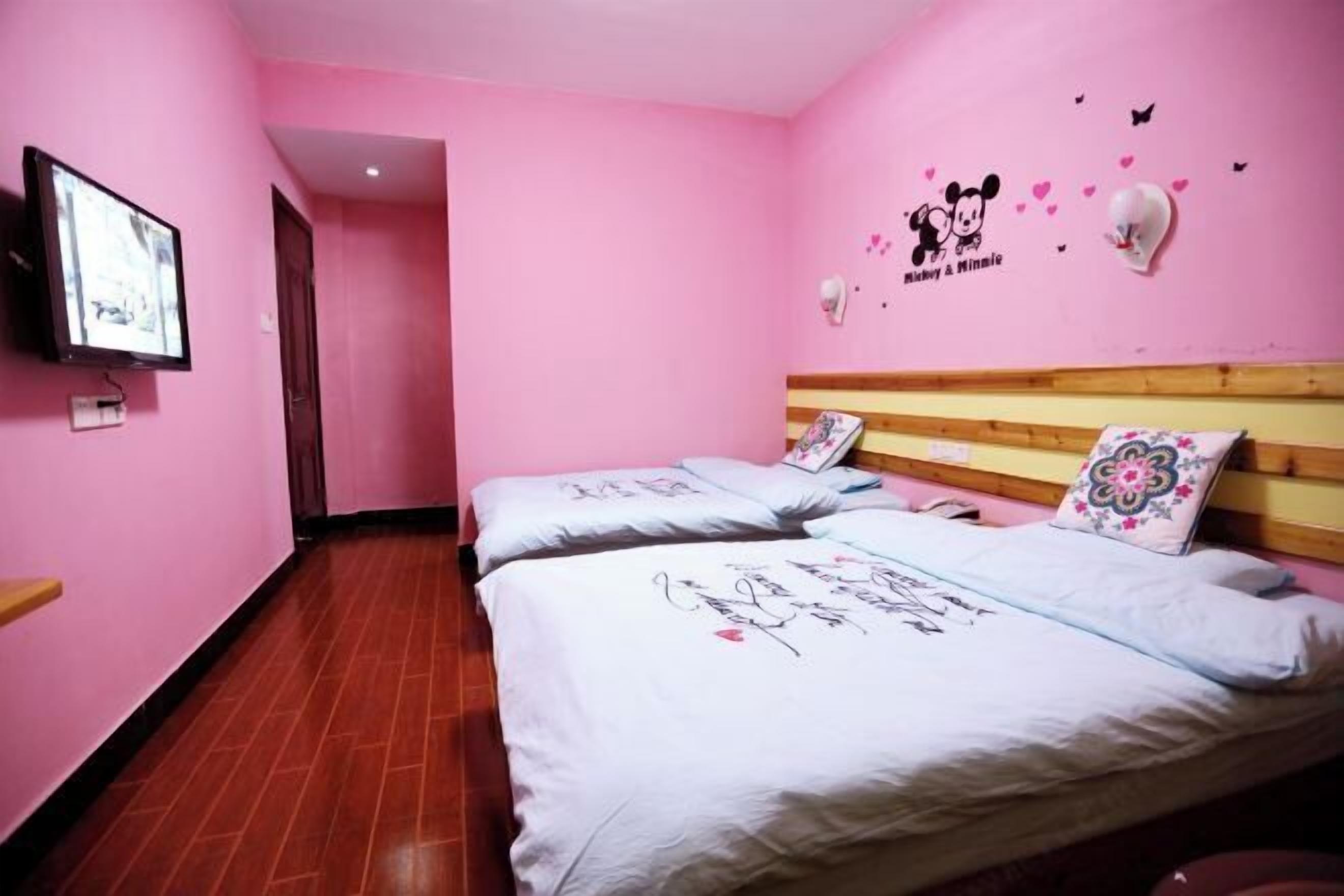 Una stanza in rosa con due letti, televisore e decorazioni a tema Minnie Mouse.
