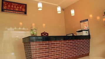 A reception desk with a brick base and a black countertop, three pendant lights above, and a framed sign on the wall.