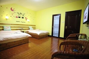 A room with two beds, a wooden floor, a door, and a wall decoration. - Haiyun Inn (Huangshan City)