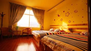 A hotel room with a bed, a desk, a chair, a window with curtains, and a wall with star decorations.