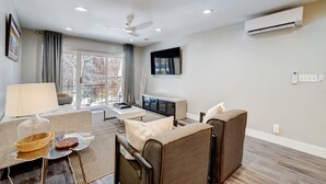 Ein modernes Wohnzimmer mit einer Couch, einem Couchtisch, einem Fernseher und einem Deckenventilator.