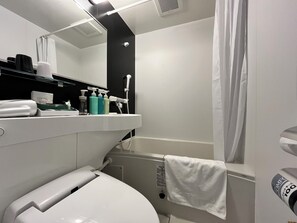 Een moderne badkamer met toilet, wastafel en douche. Er staan toiletartikelen op de wastafel en een handdoek hangt aan het douchegordijn.