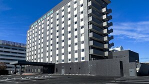 A multi-story hotel with a modern design, featuring a prominent sign at the top. - Hotel Route Inn Miyakonojo (Miyakonojo)