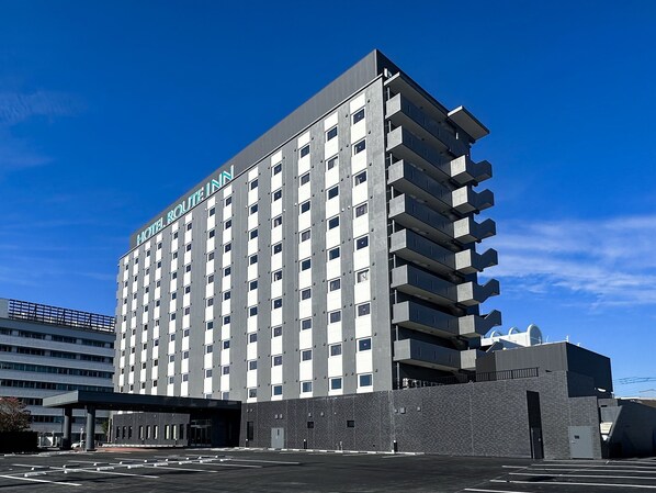 Een meerlaags hotel met een modern design, met een opvallend bord bovenaan.