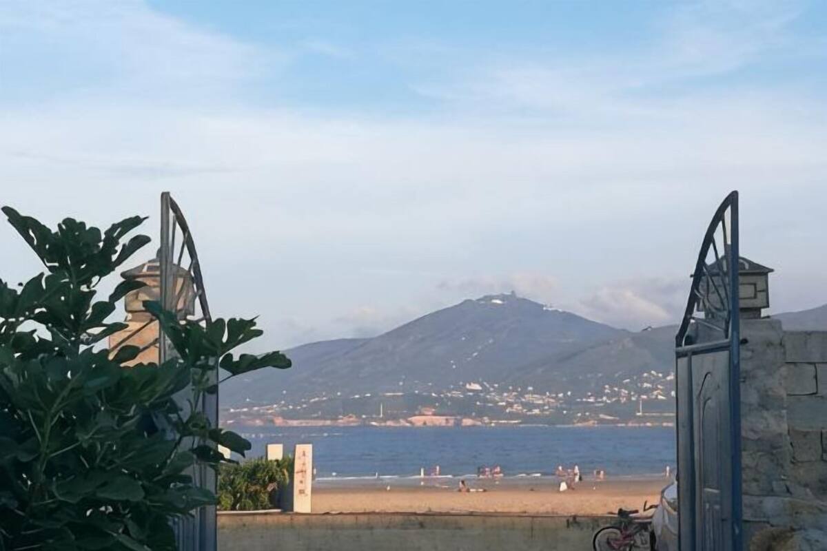 Une vue cĂŽtiĂšre avec une montagne en arriĂšre-plan, une plage et une porte.