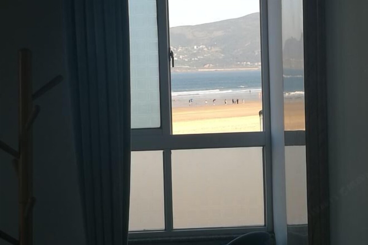 Una habitación con un amplio ventanal que da a la playa.