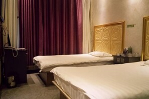 A hotel room with two beds, a wooden headboard, a small table, and a suitcase. - Qianxi Theme Hotel (Tailai)