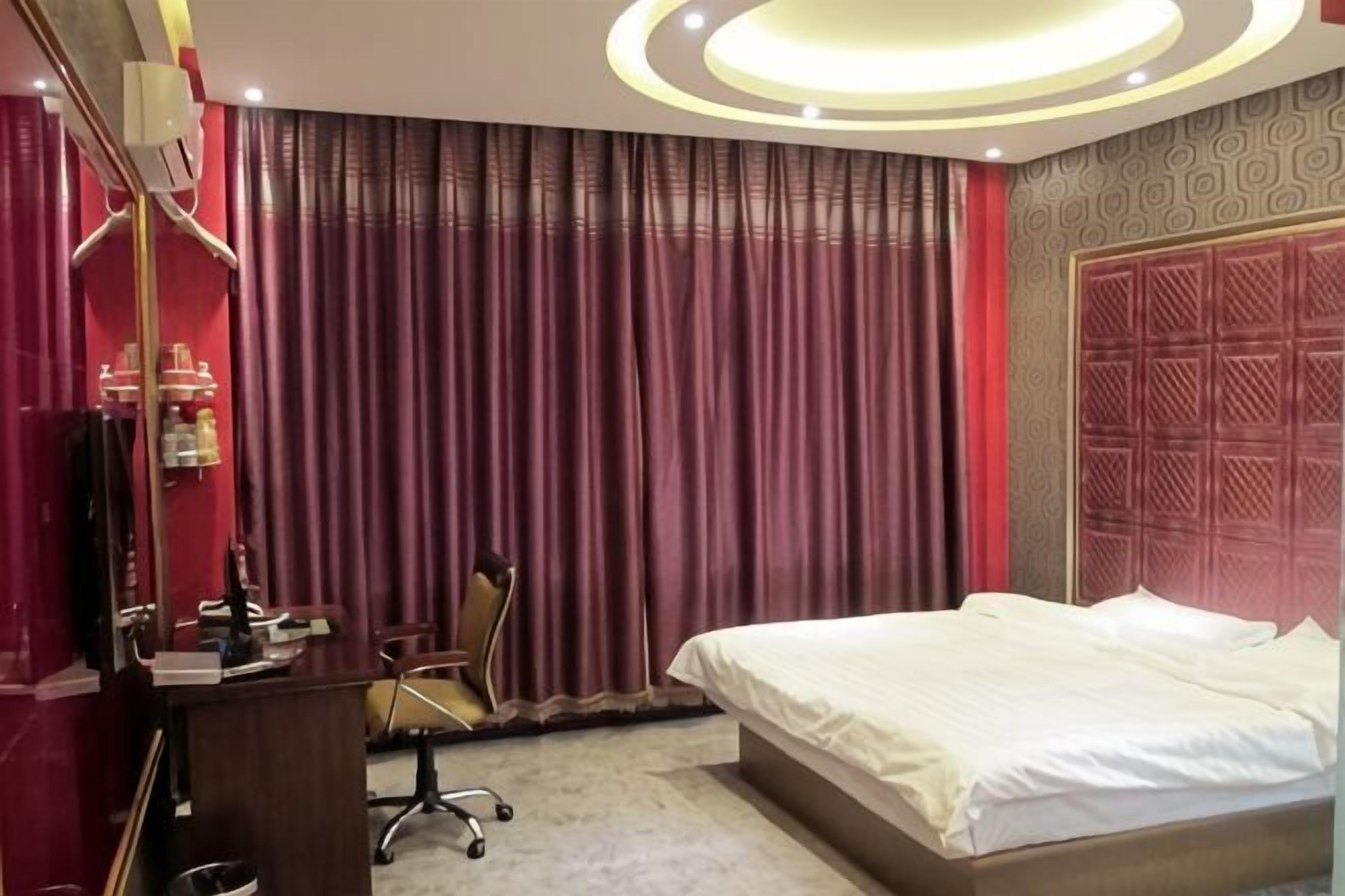 Habitación de hotel con cama, escritorio, silla y cortinas.