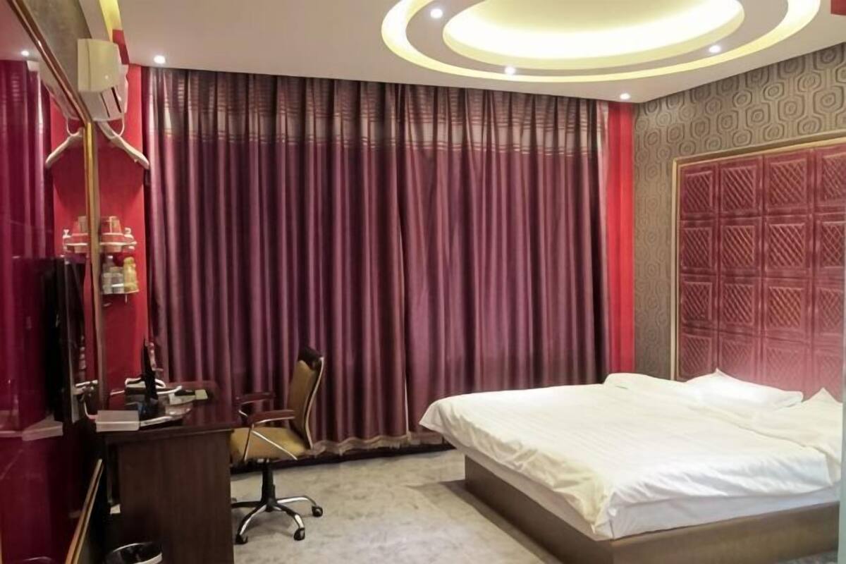 Een hotelkamer met een bed, bureau, stoel en gordijnen.