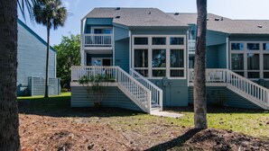 A two-story building with a blue exterior, a balcony on the second floor, and a white staircase leading to the entrance. - 493 Egrets Pointe-Beautiful Townhome on Lagoon; Pool/Amenity Access Included (Edisto Beach)