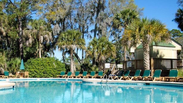 A pool area with lounge chairs and a building in the background. - 493 Egrets Pointe-Beautiful Townhome on Lagoon; Pool/Amenity Access Included (Edisto Beach)