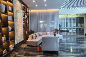 A modern living room with a sectional sofa, a coffee table, and a bookshelf. - XiaoNanJing Fashion Hotel (Shangli)
