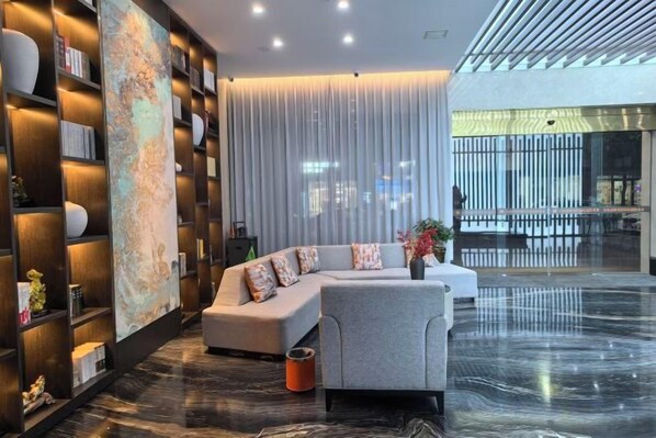 A modern living room with a sectional sofa, a coffee table, and a bookshelf. - XiaoNanJing Fashion Hotel (Shangli)