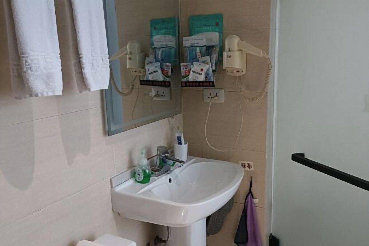 Un bany amb un lavabo blanc, un mirall i un suport per a tovalloles.